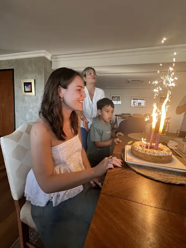 Agus sonriendo frente a su torta de cumpleaños con bengalas