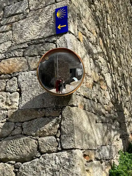 Reflejo de Agus y Enzo bajo una señal del Camino de Santiago